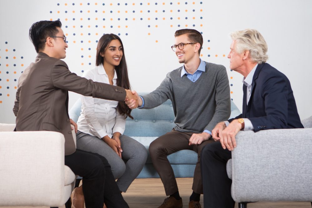 smiling-business-partners-shaking-hands-lounge
